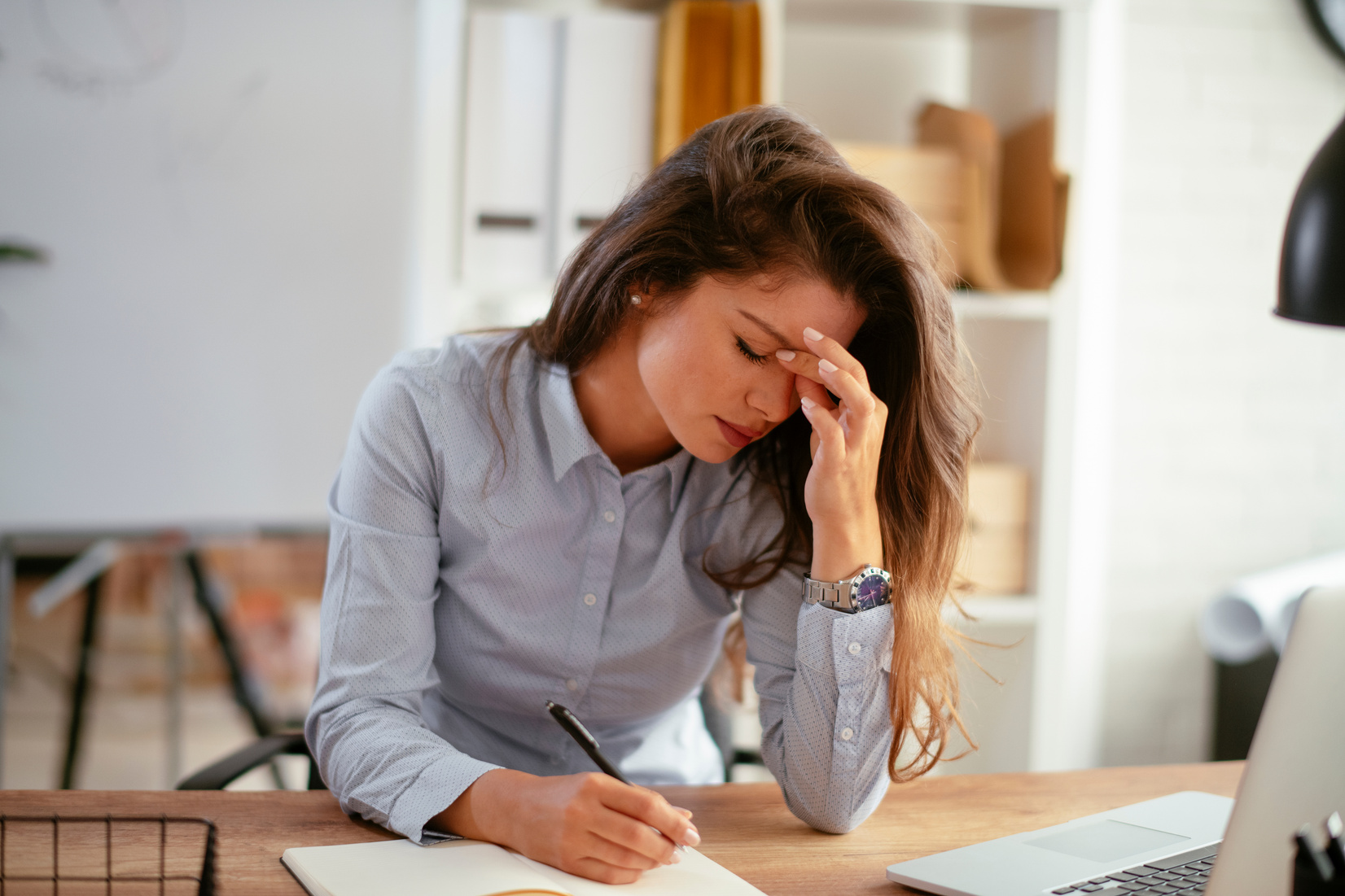 Female entrepreneur with headache sitting at desk. stock photo